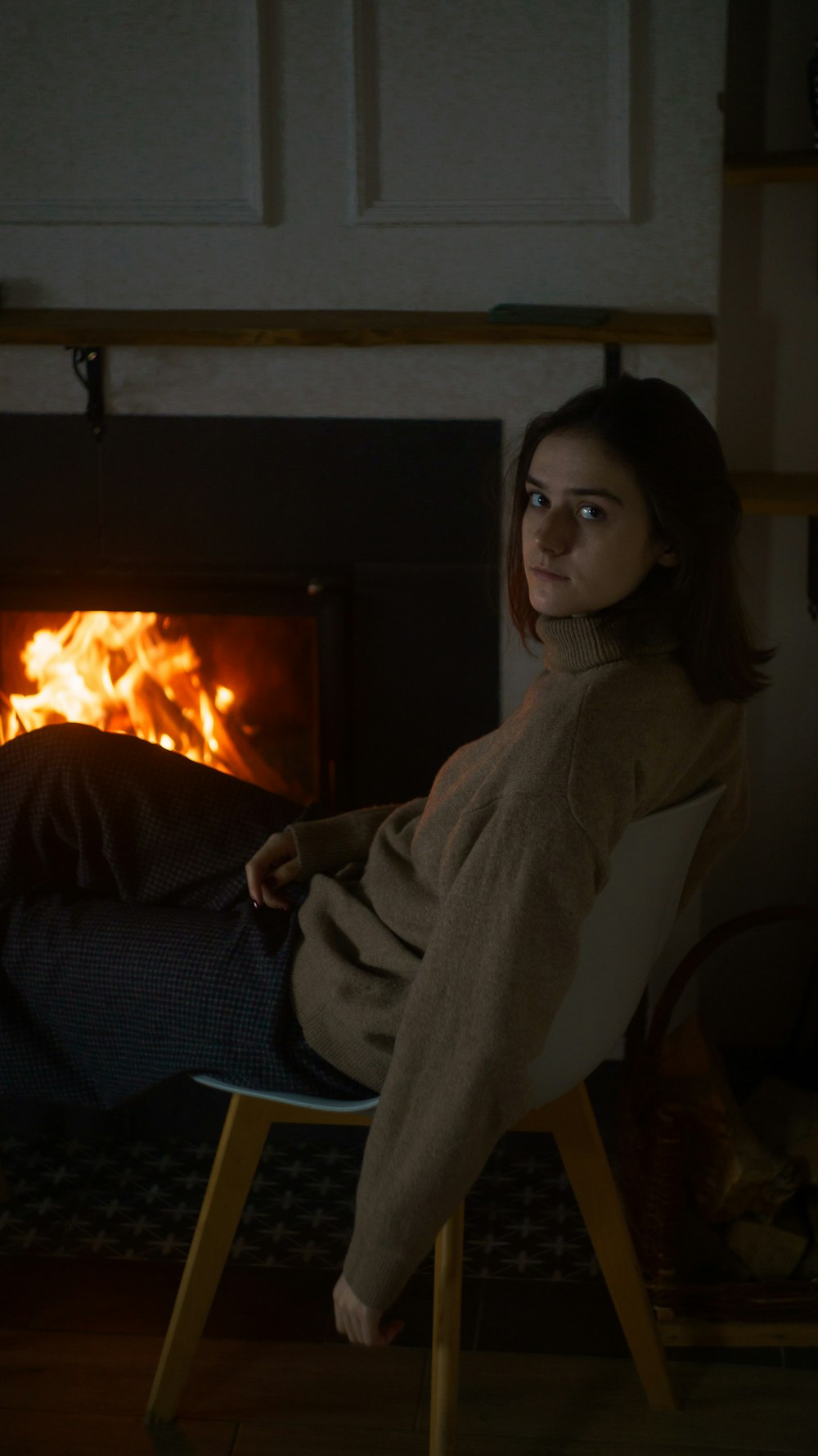 a woman sitting in a chair in front of a fire