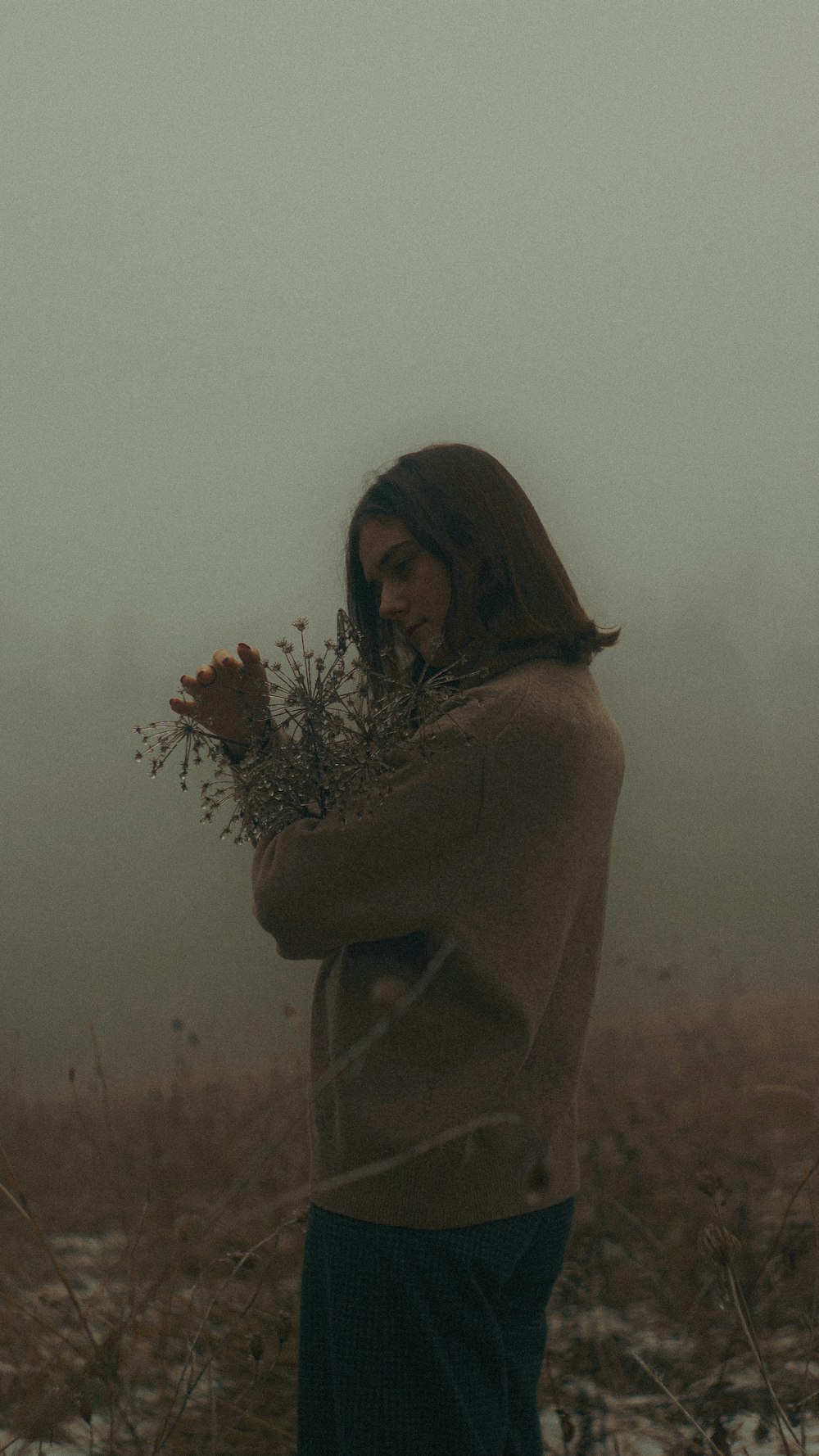 a woman standing in a field holding a plant