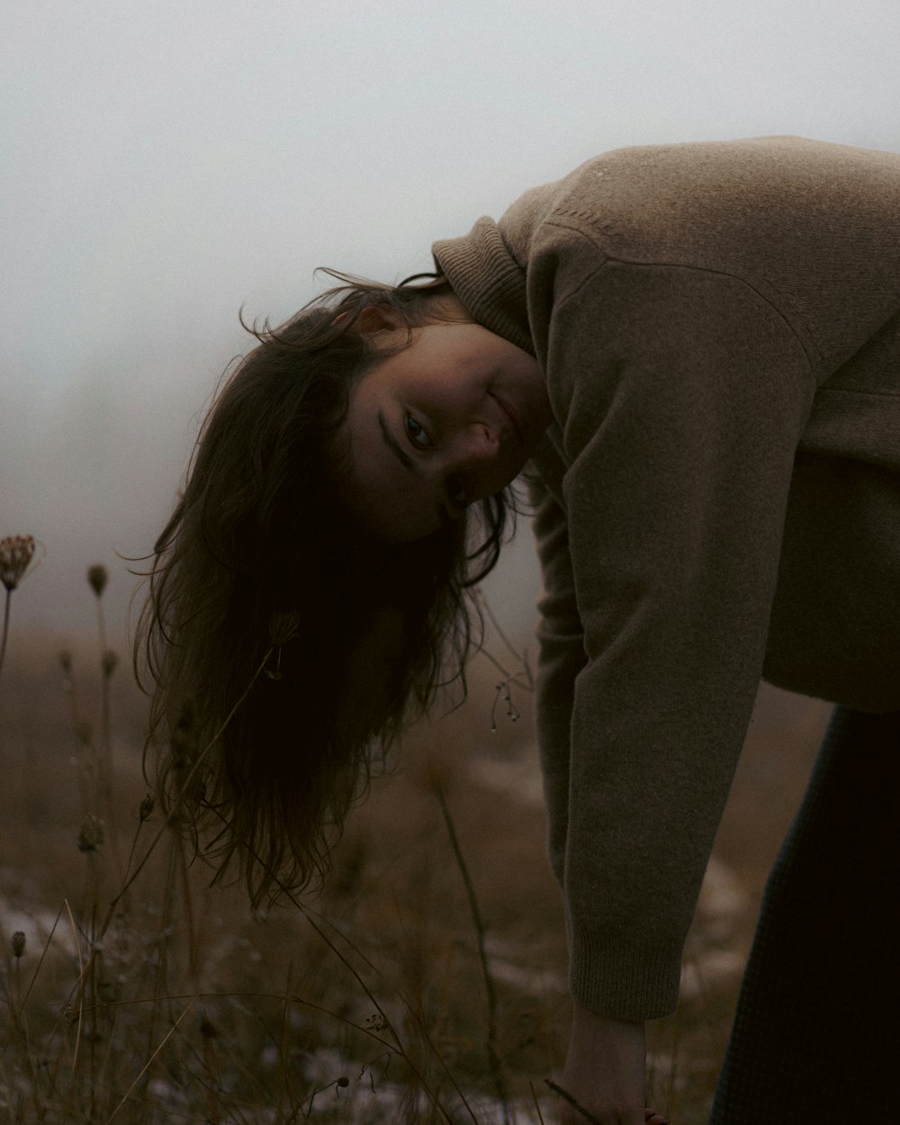 a woman is bending over in a field