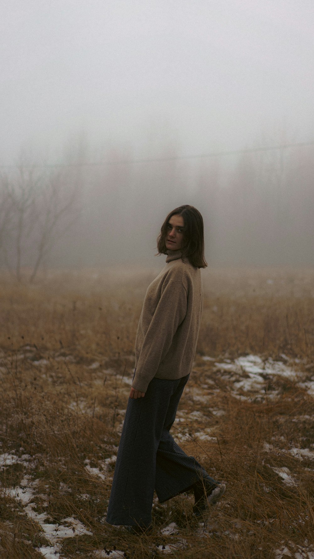 a woman standing in a field in the fog