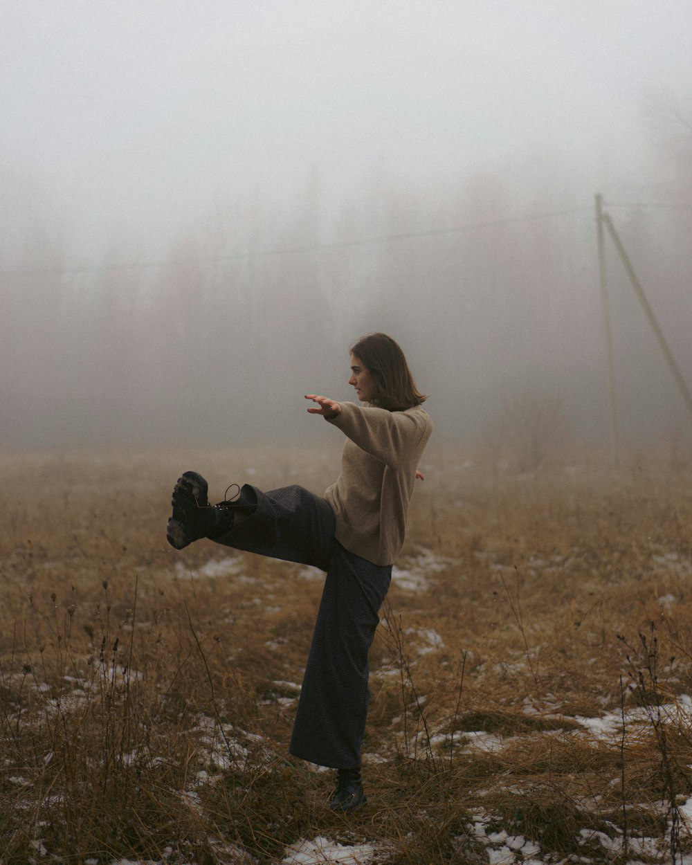 a woman standing in a foggy field with her leg in the air