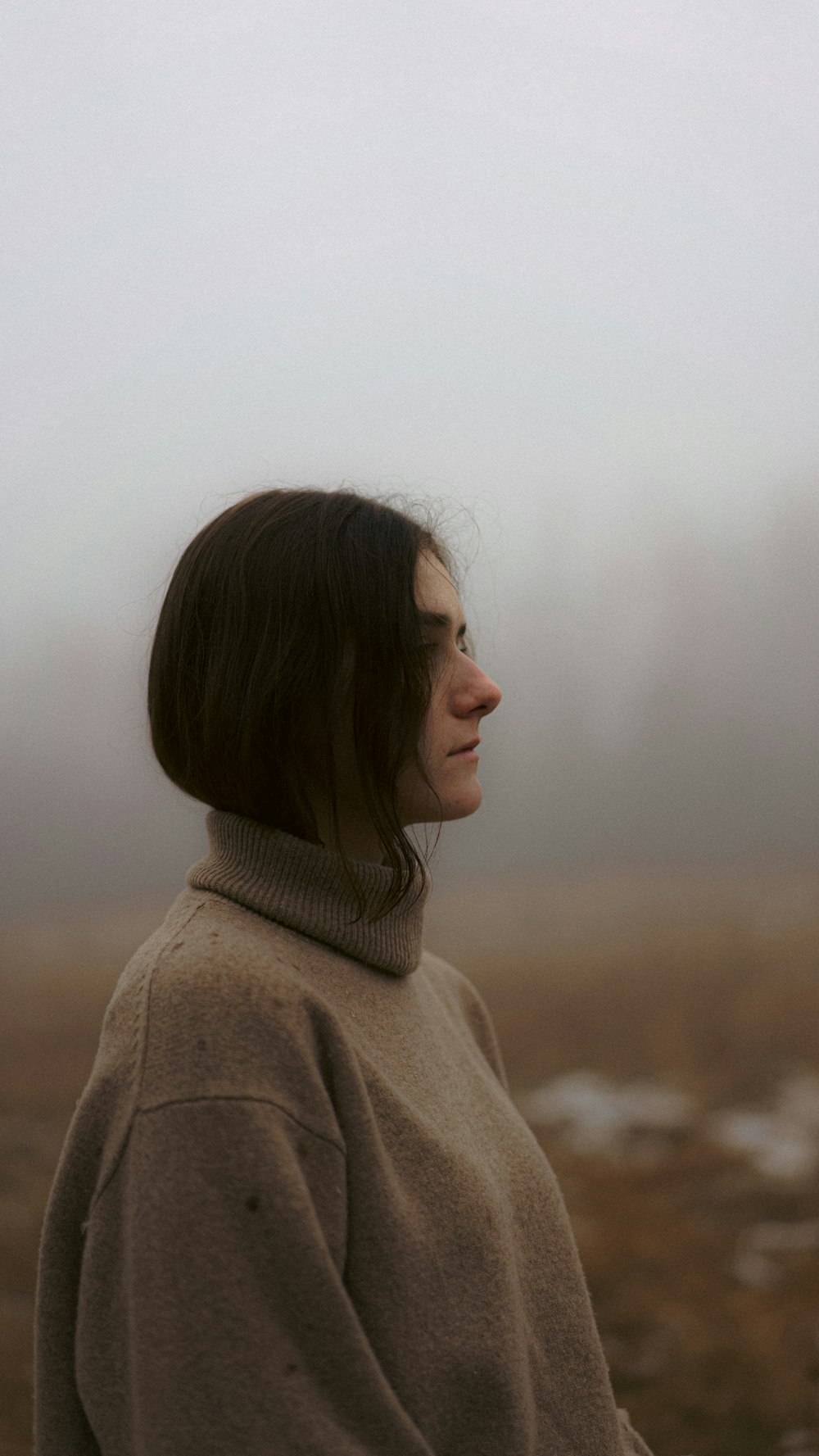 a woman standing in a field in the fog