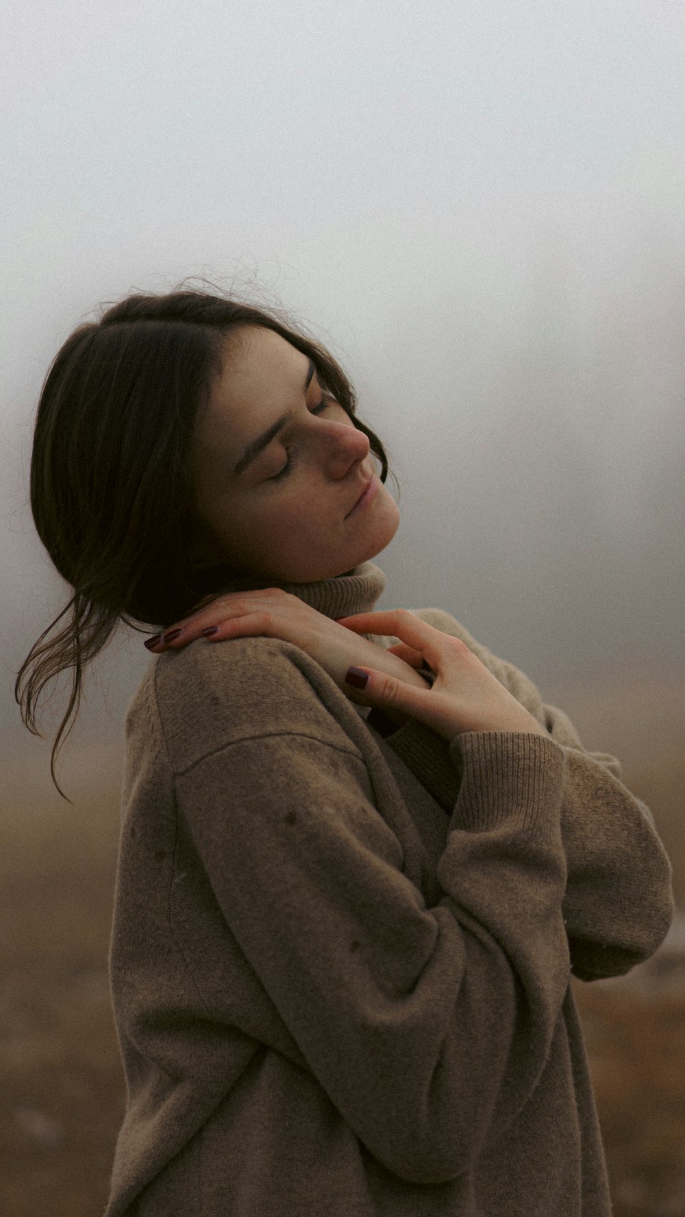 a woman standing in a field with her eyes closed