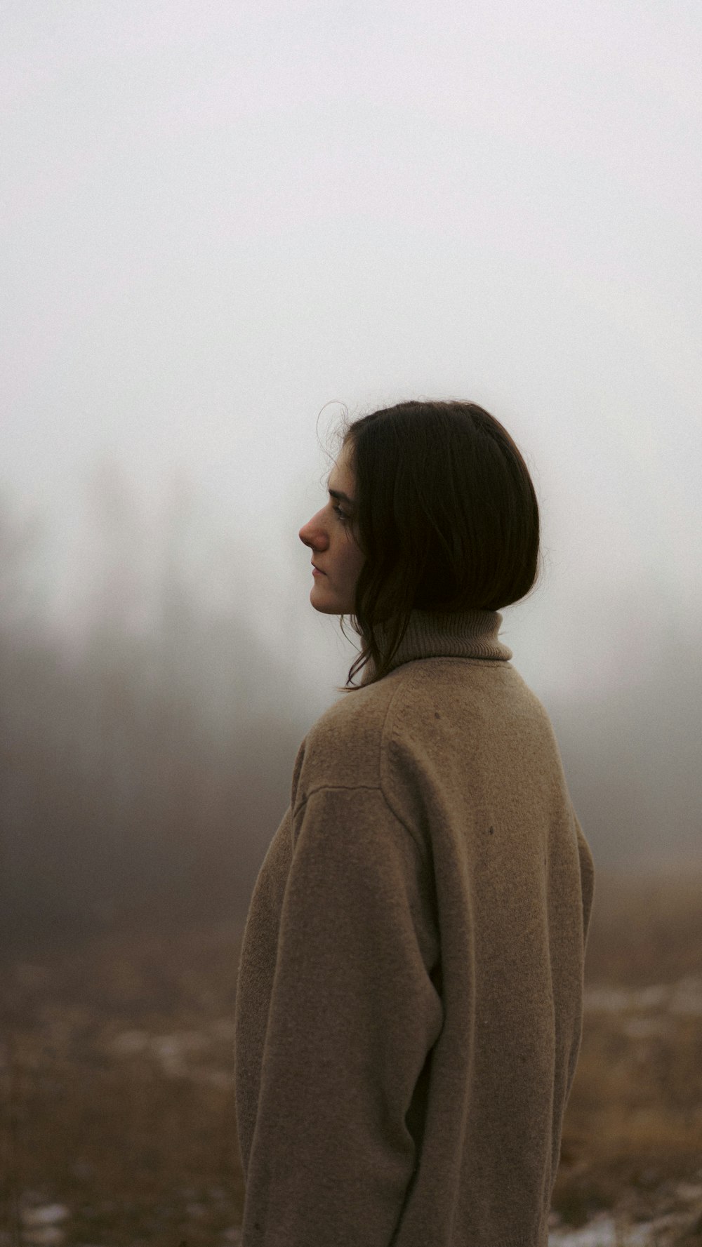 a woman standing in a field in the fog