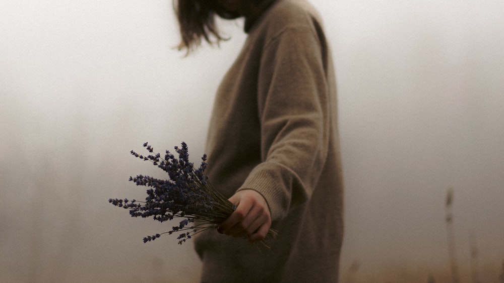 a woman holding a bunch of flowers in her hands