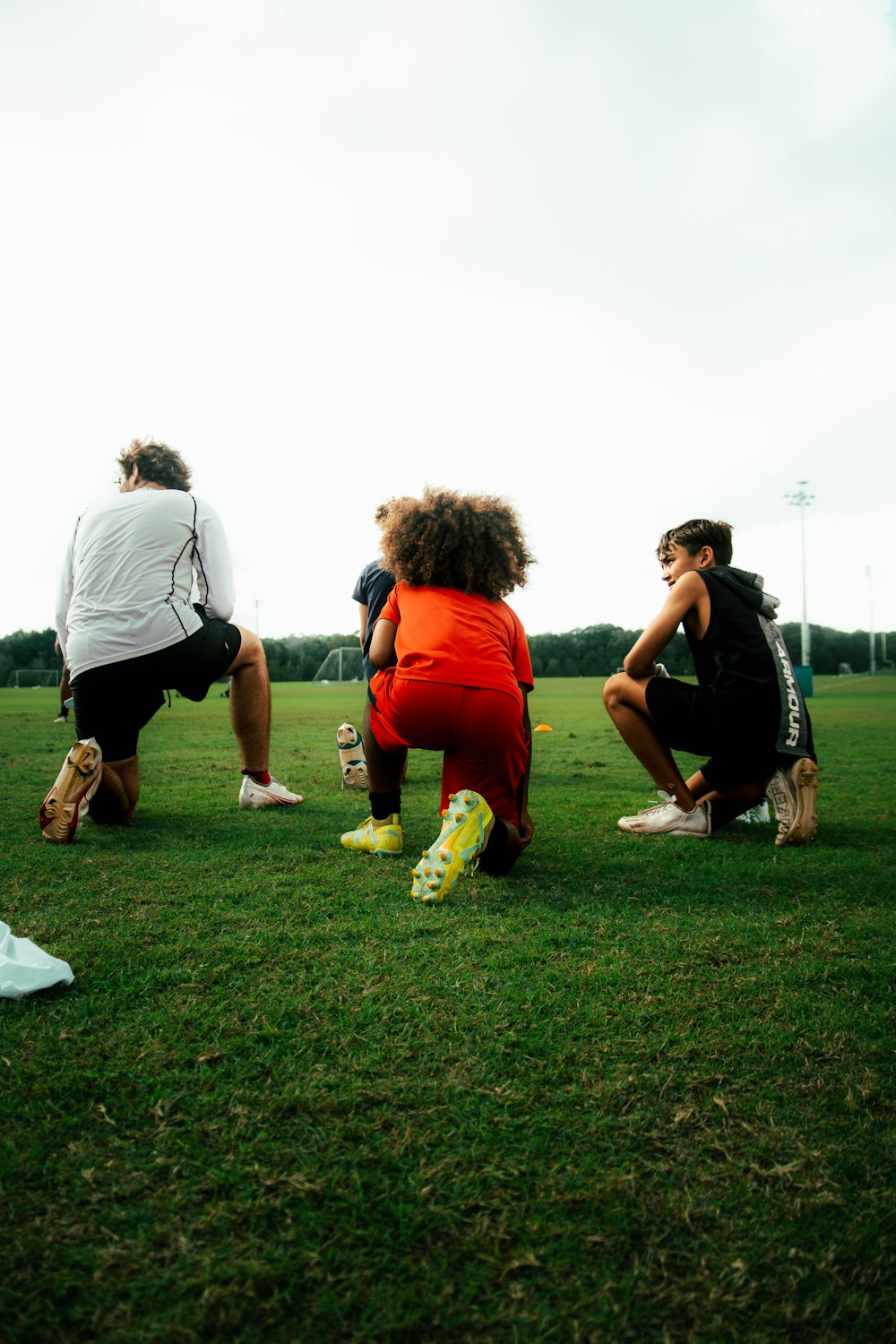 a group of people sitting on top of a lush green field