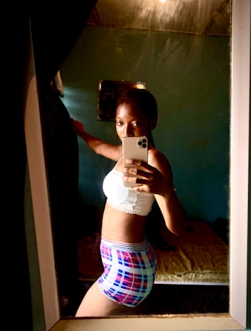 A user taking a selfie with a smartphone camera in a bright, minimalistic room.