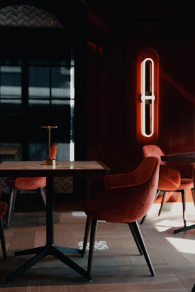 A sleek, obsidian-black dining room illuminated by glowing neon accents in saffron, jade, and cobalt hues.