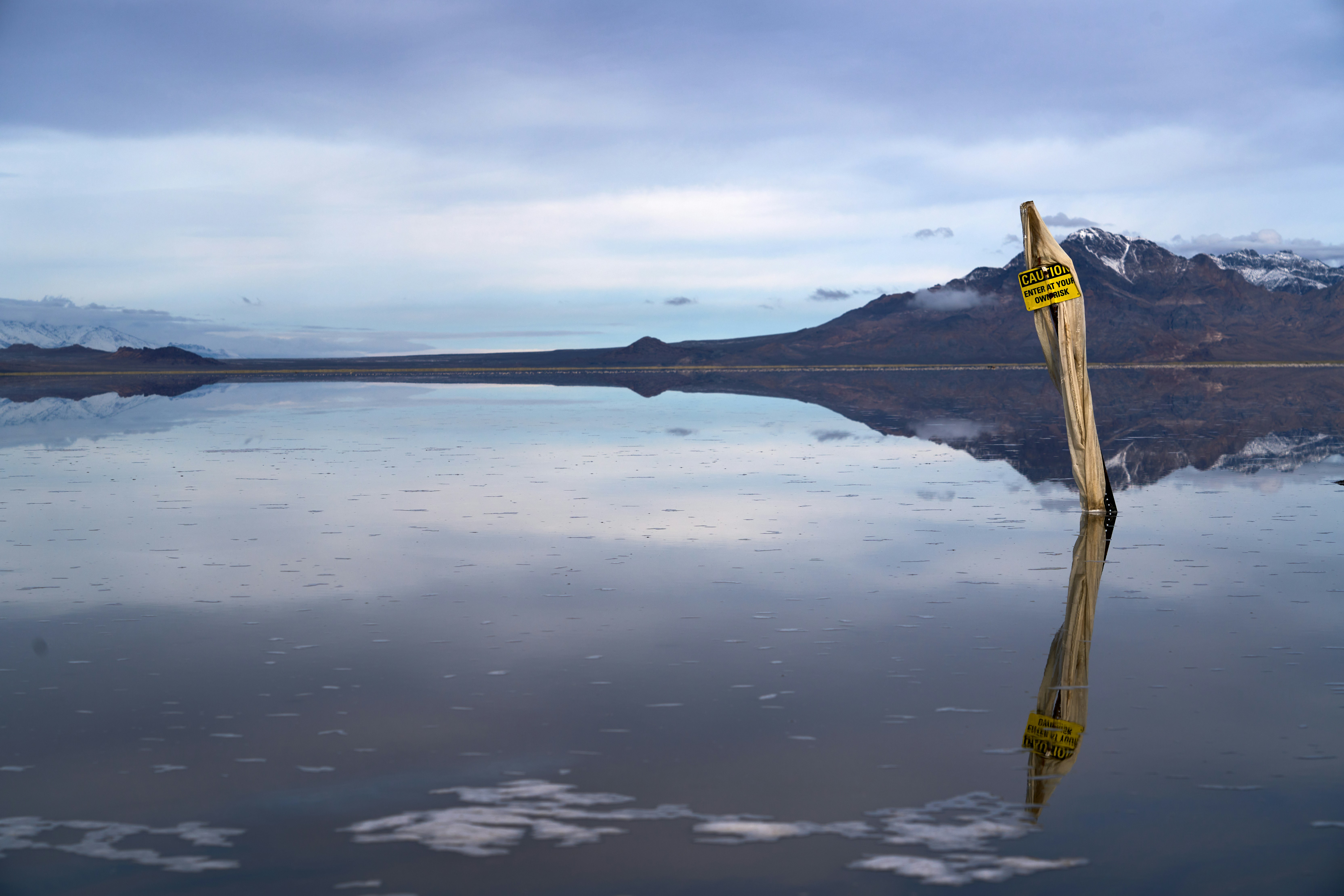 a pole sticking out of the water with mountains in the background