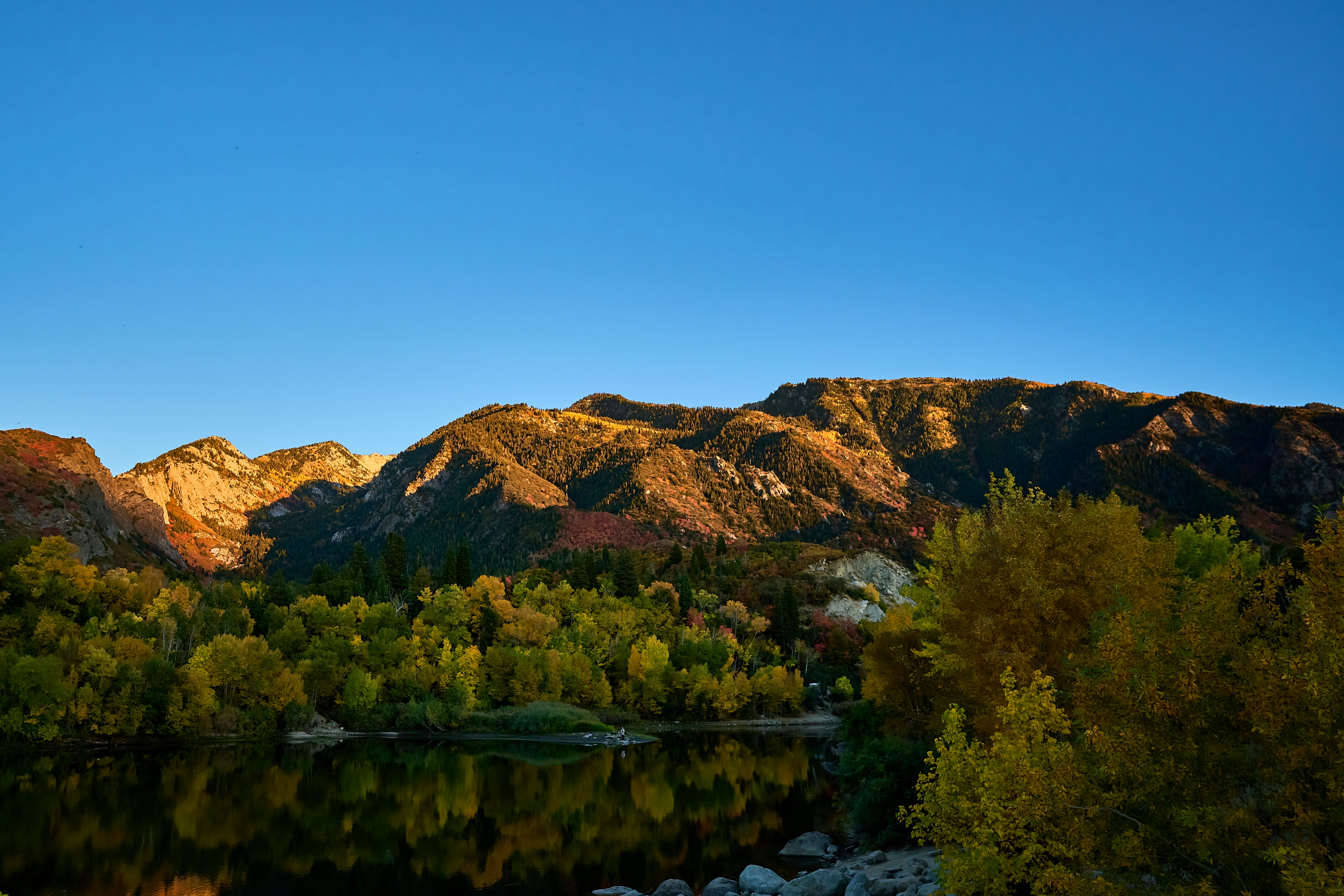 a lake surrounded by mountains with trees in the foreground