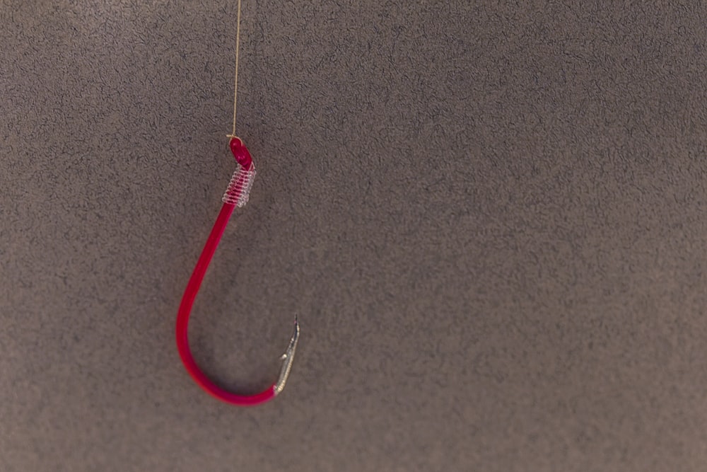 um anzol de pesca vermelho pendurado em um anzol