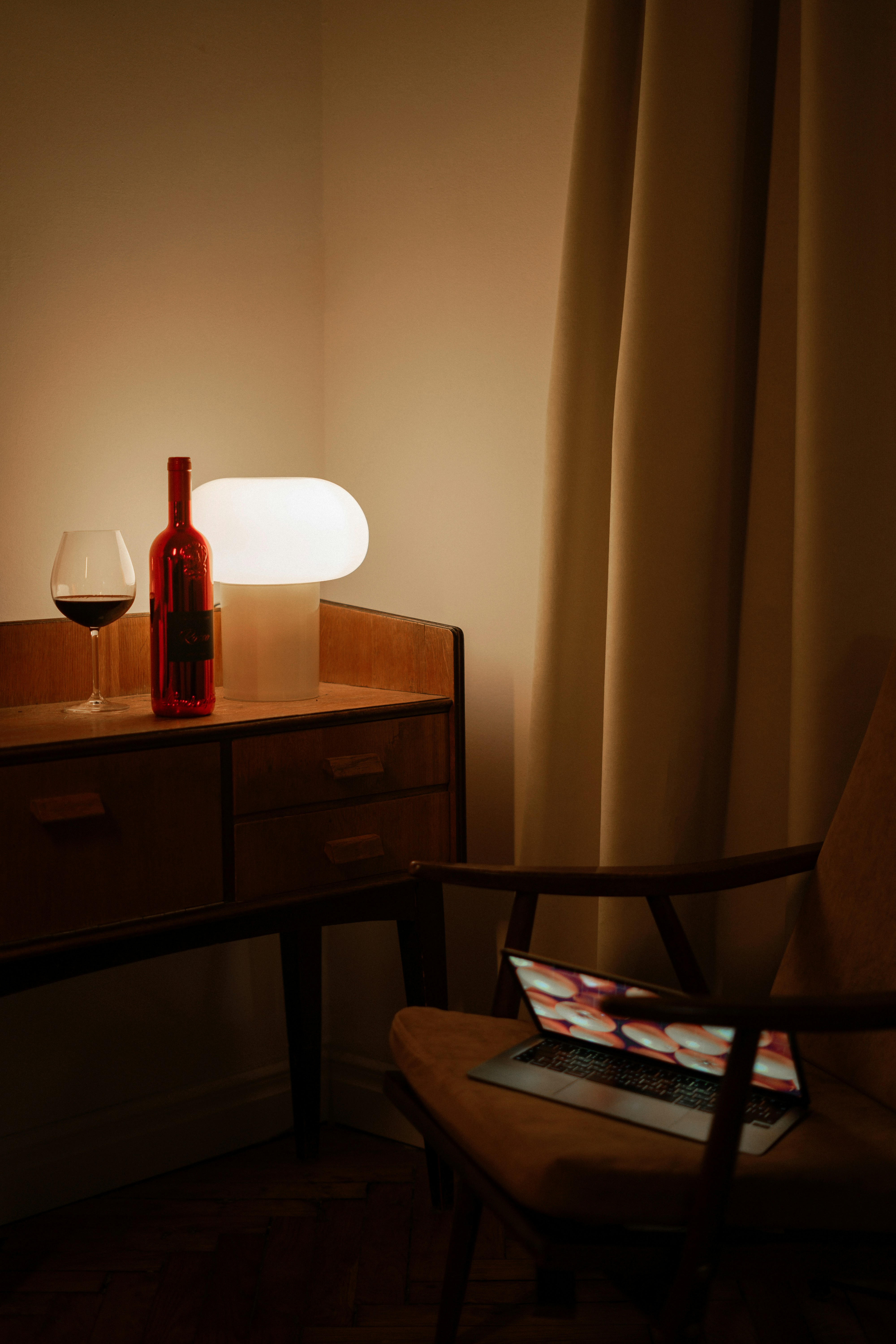 a bottle of wine sitting on a table next to a lamp