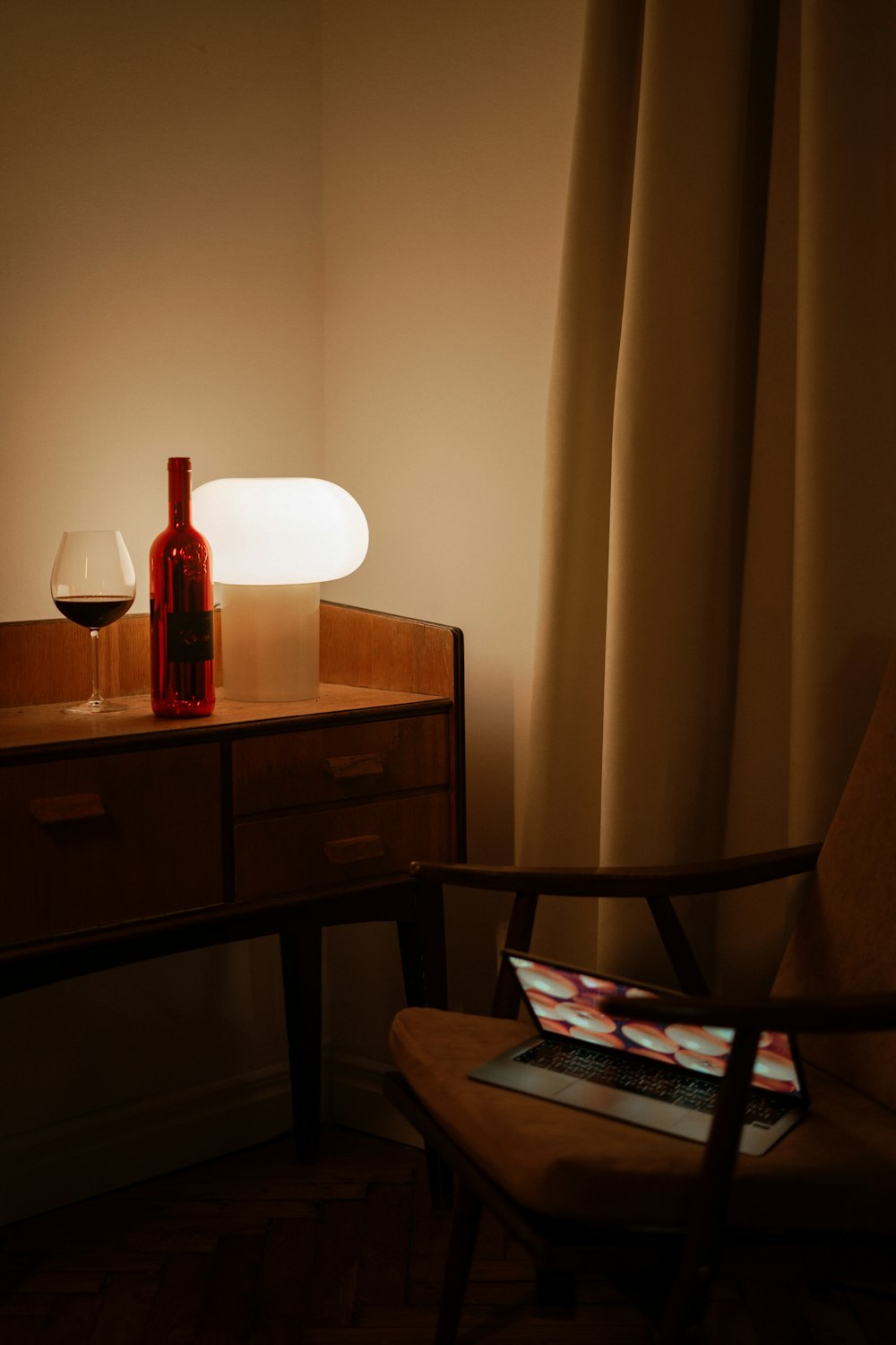 a bottle of wine sitting on a table next to a lamp