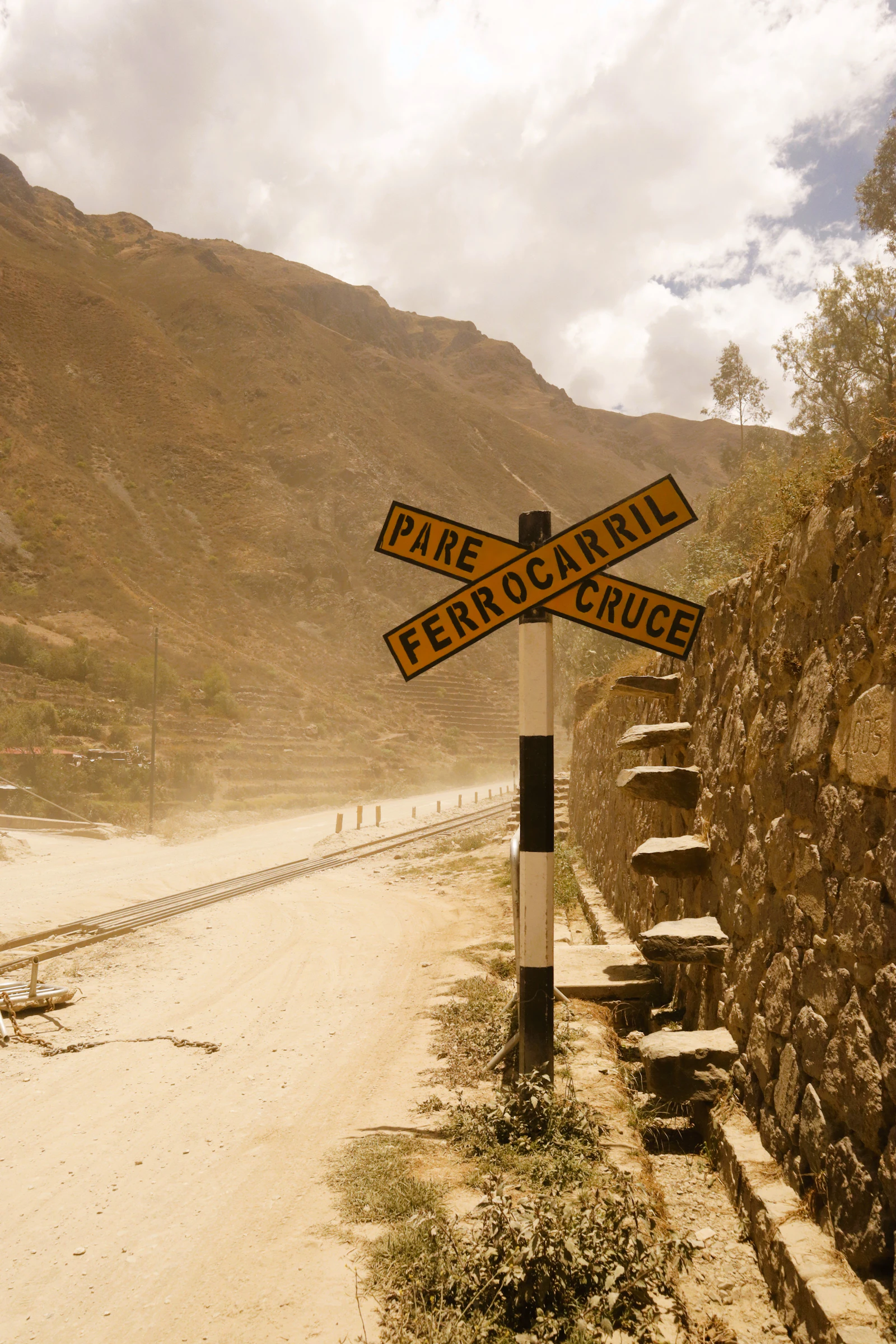 A railway-crossing sign beside a rural road near Ollantaytambo