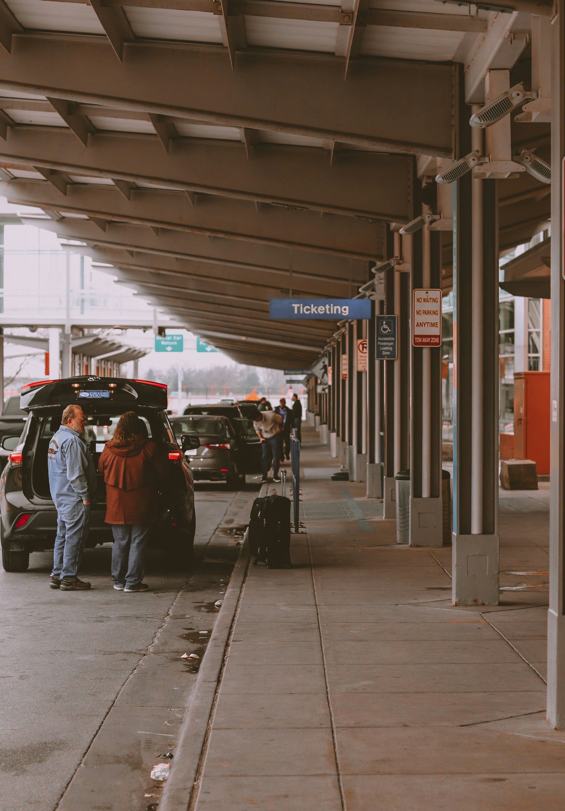 a group of people standing next to a parked car