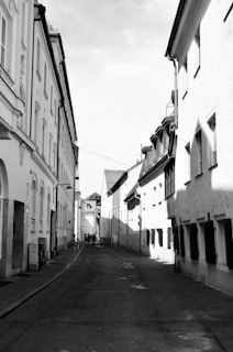 A stark black and white photograph capturing a quiet street scene in Bulgaria, with soft shadows and textured walls.