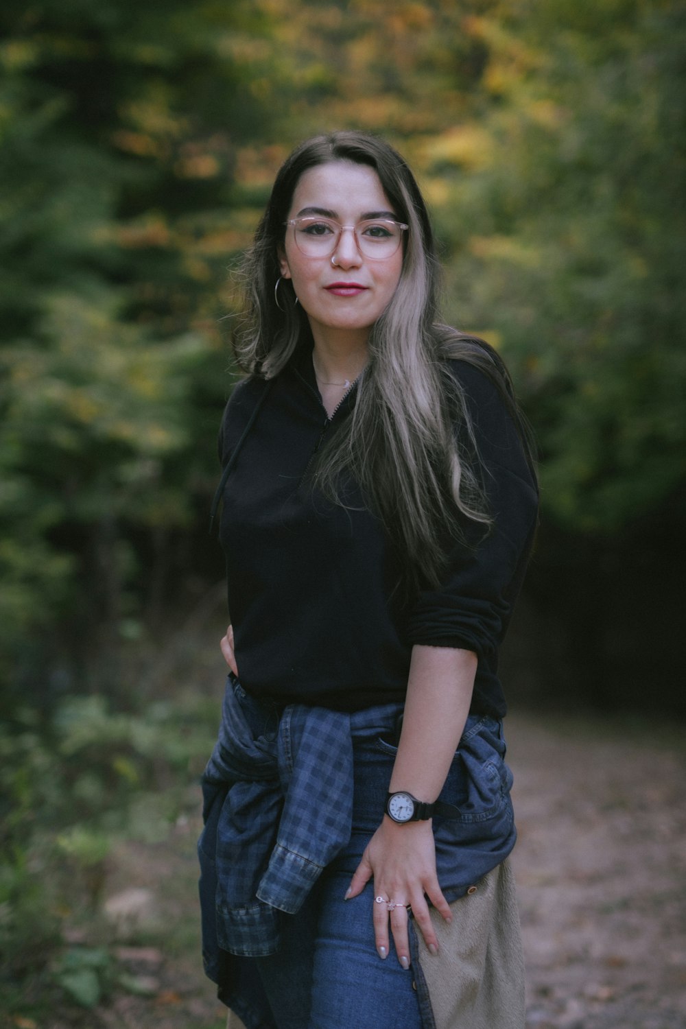 a woman standing in the woods with her hands on her hips