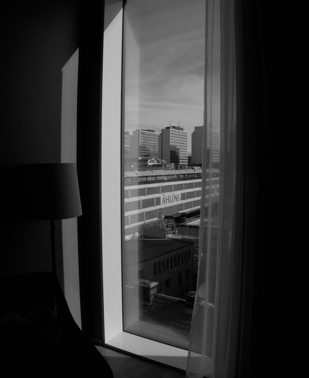 a black and white photo of a window with a view of a city