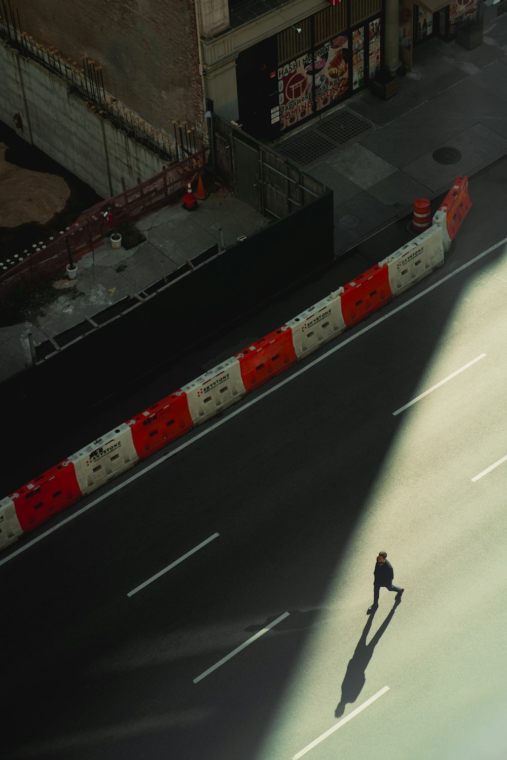 a man walking down a street next to a tall building