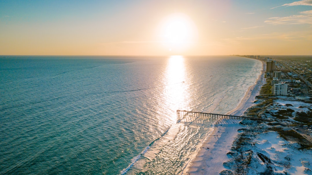 an aerial view of a beach and ocean at sunset,