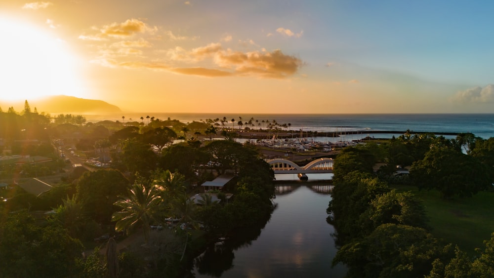 the sun is setting over a river and a bridge