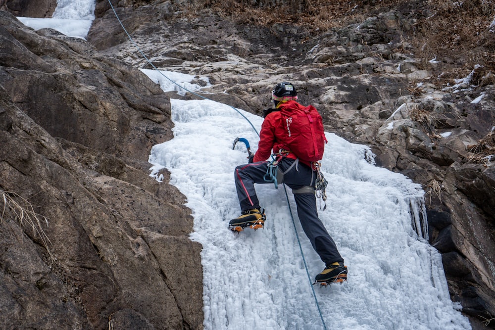 a man in a red jacket climbing up a mountain