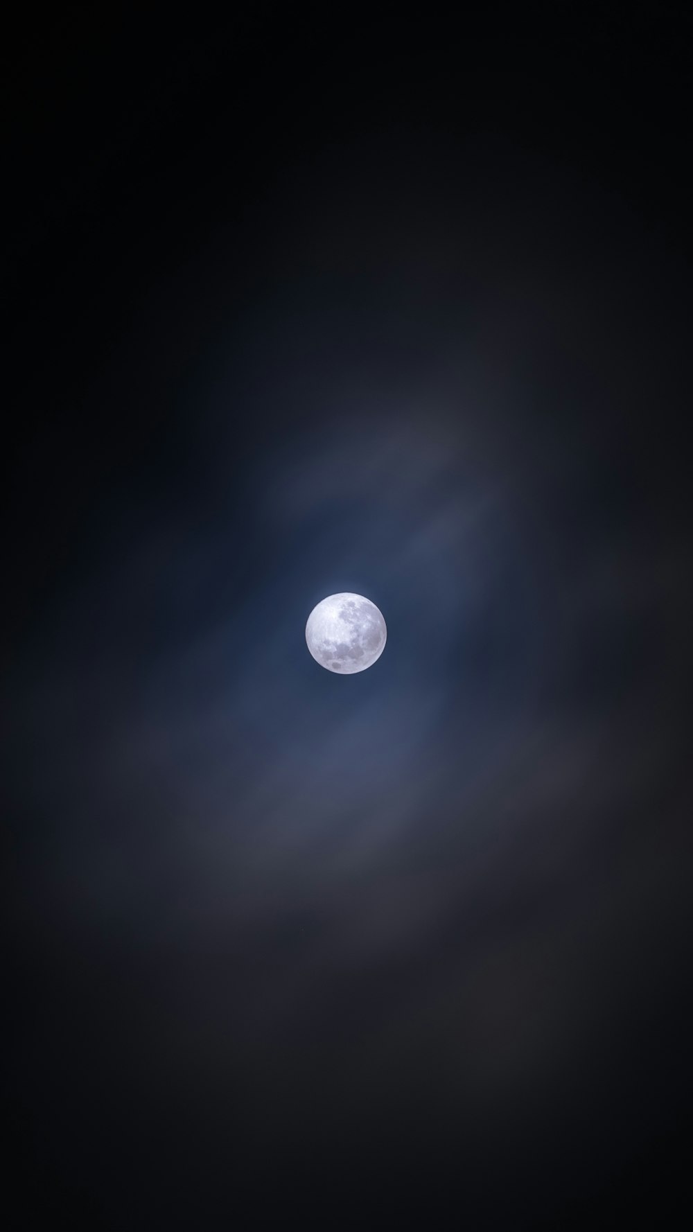 a full moon seen through the clouds in the night sky