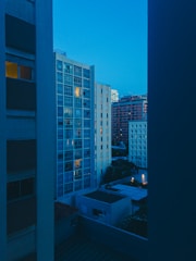 A panoramic view of a high-rise residential tower lit warmly at dusk.