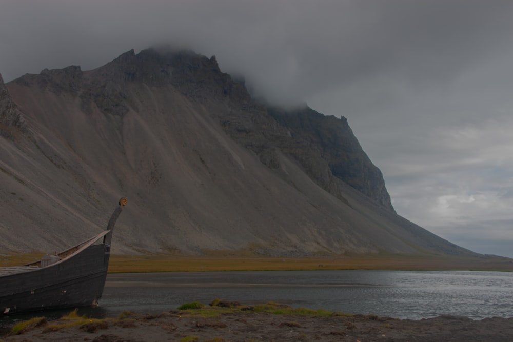 a boat sitting on top of a beach next to a mountain