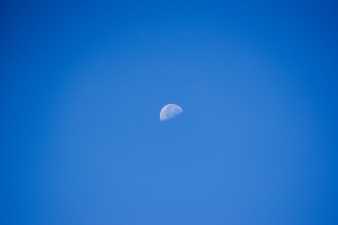 a half moon in a clear blue sky,