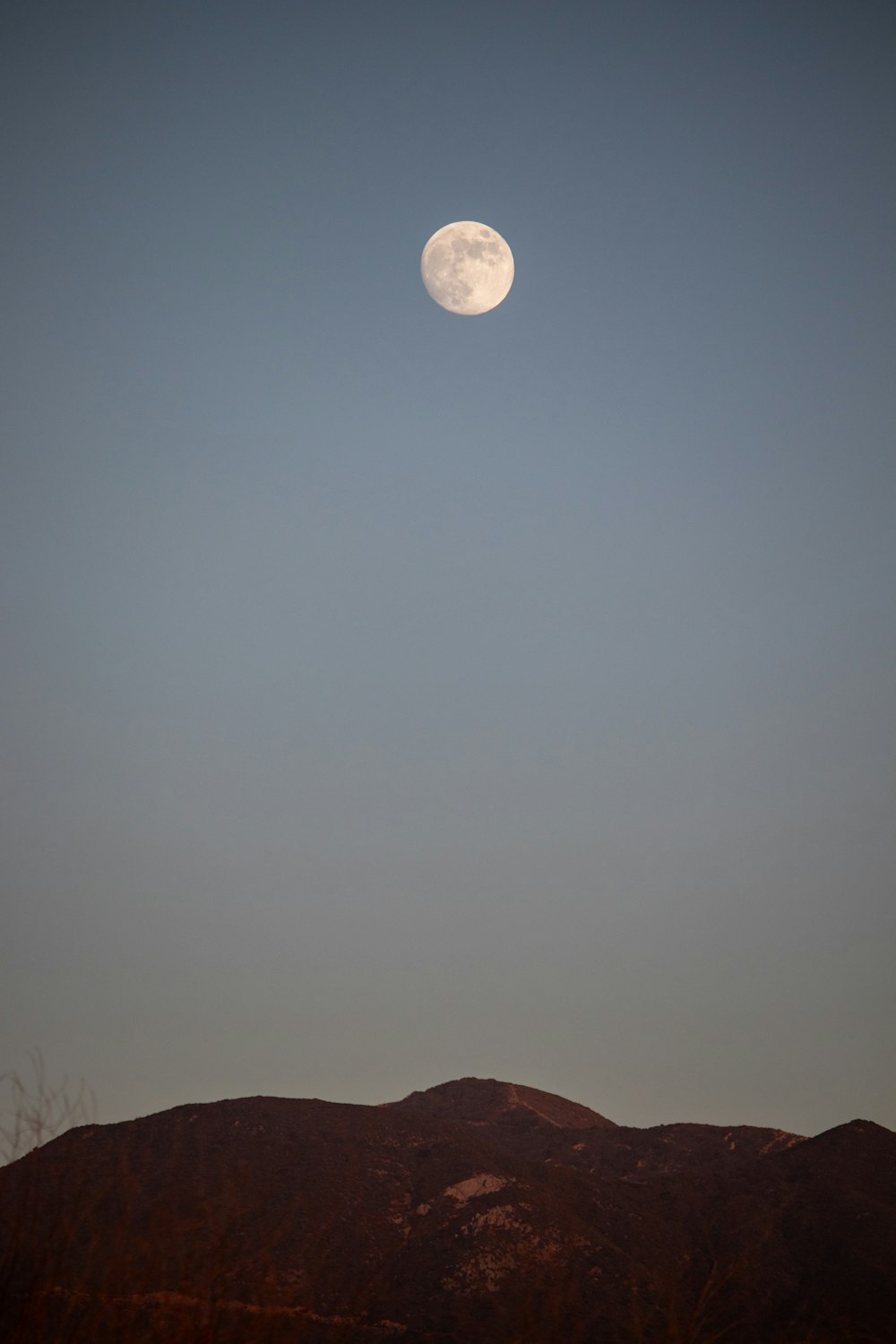 a full moon rising over a mountain range