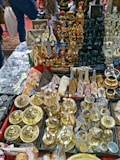 A collection of various souvenirs and artifacts, including golden pots, statuettes resembling ancient Egyptian figures, pyramids, and other intricately designed decorative items spread across a table. The assortment displays a mix of metal, wood, and stone objects with a focus on Egyptian-themed cultural motifs.