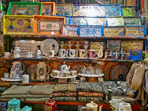 Hand-painted trays with detailed cultural patterns, arranged neatly with brass decor items reflecting Varanasi’s heritage