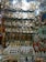 An artisanal display with intricately designed metal plates featuring elaborate engravings, ornate boxes, and various traditional items. The arrangement also includes small pyramidal souvenirs and mugs with decorative motifs, set against a glass shelf backdrop.