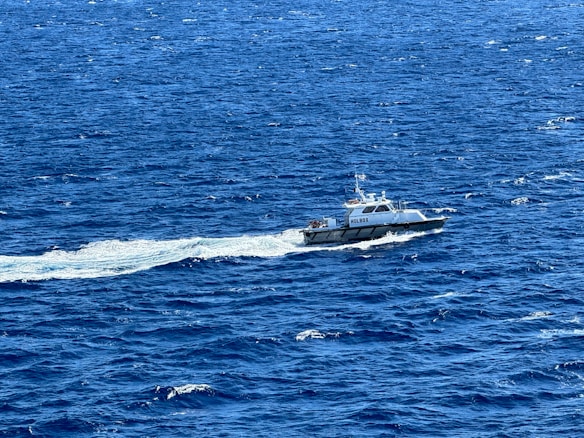 A boat labeled 'Holbox' moves through a vast expanse of deep blue water, creating a white wake behind it as it navigates across the ocean.