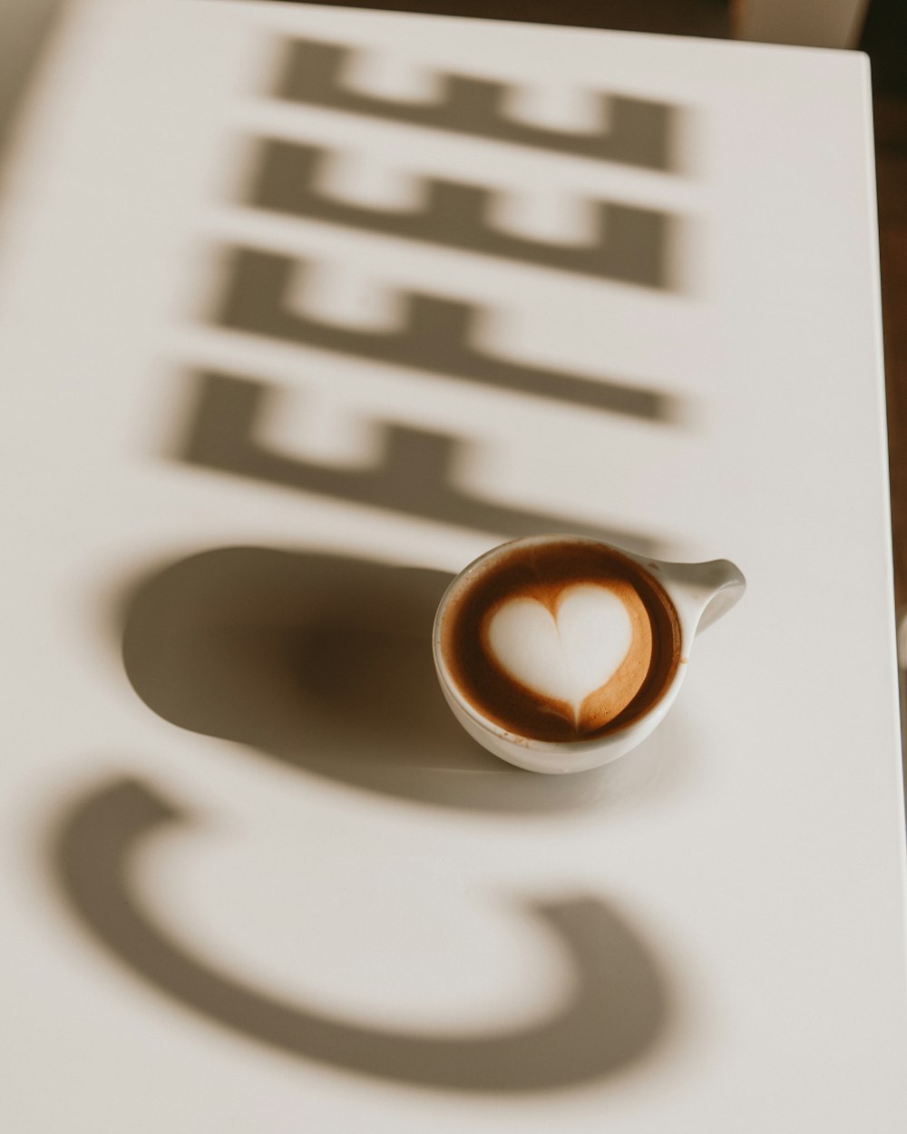 a cup of coffee on a table with a shadow