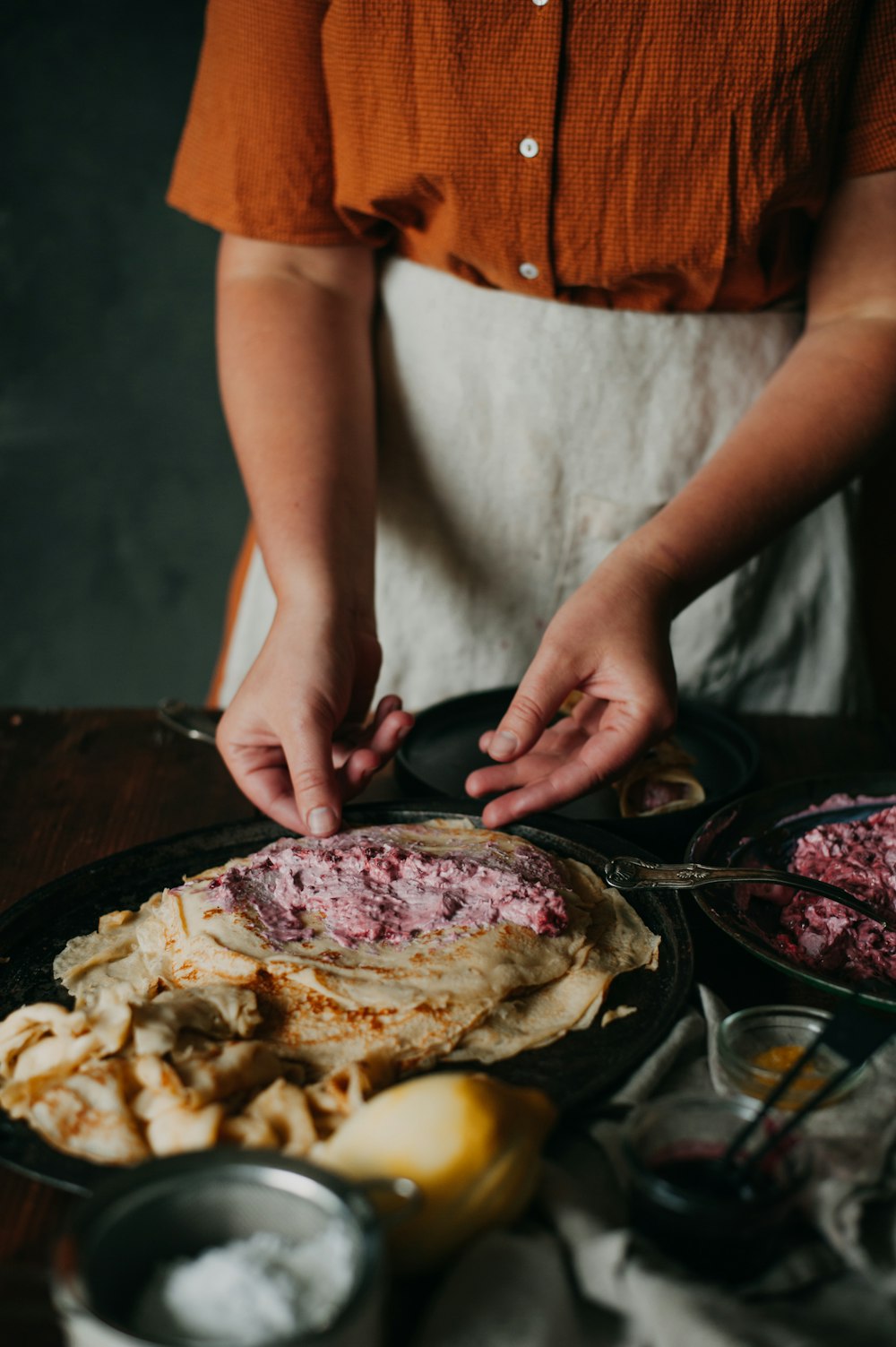 a woman in an orange shirt is preparing food