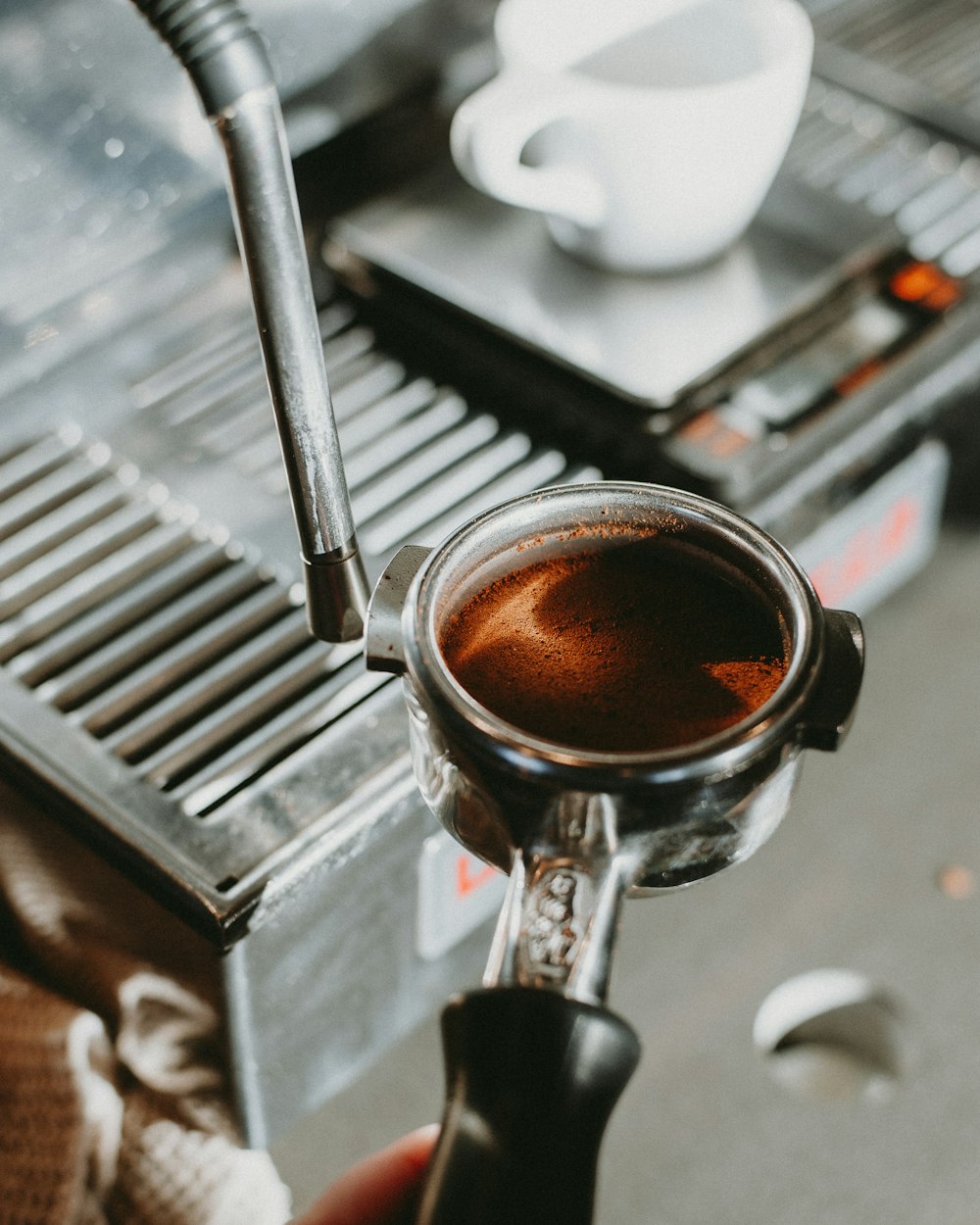 a person holding a cup of coffee in front of an espresso machine