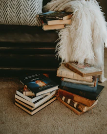 A cozy reading nook with a stack of classic novels and a warm lamp.