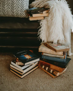 Cozy reading nook filled with stacks of classic and contemporary books, inviting a message or question.
