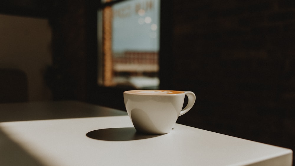 a cup of coffee sitting on top of a white table