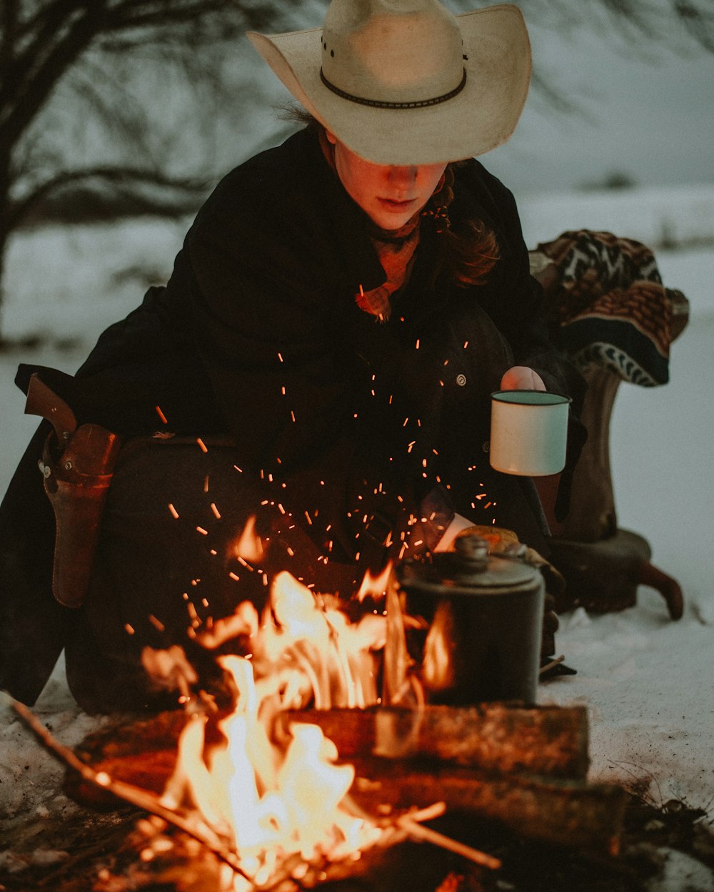 a person sitting in front of a fire with a hat on