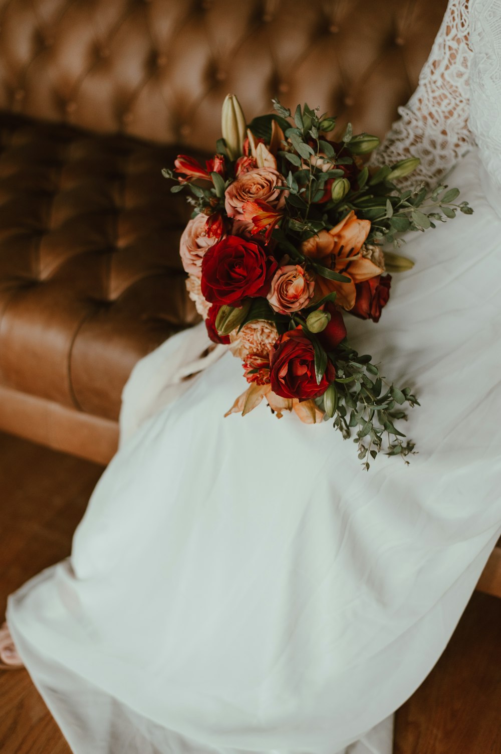 a bride sitting on a couch holding a bouquet of flowers