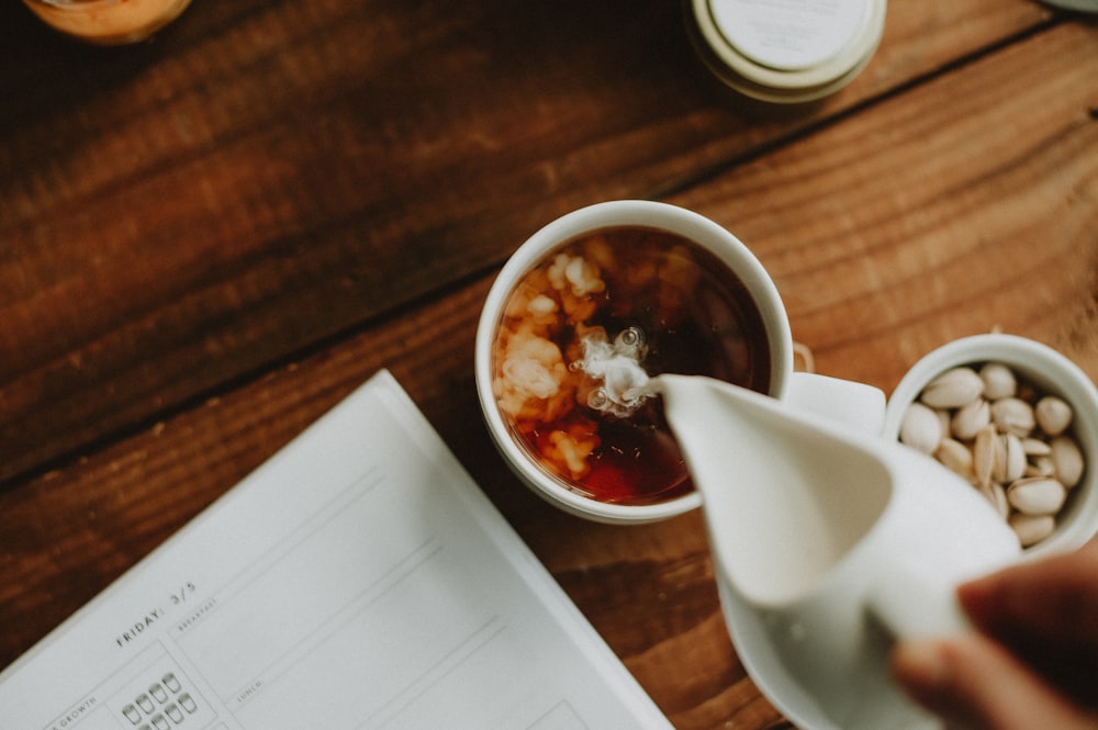 a person pours coffee into a cup on a wooden table