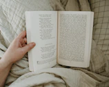 Hands holding a simple, well-worn book against a backdrop of soft linen fabric.