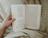 Close-up of hands holding an open chapbook against a backdrop of parchment textures.