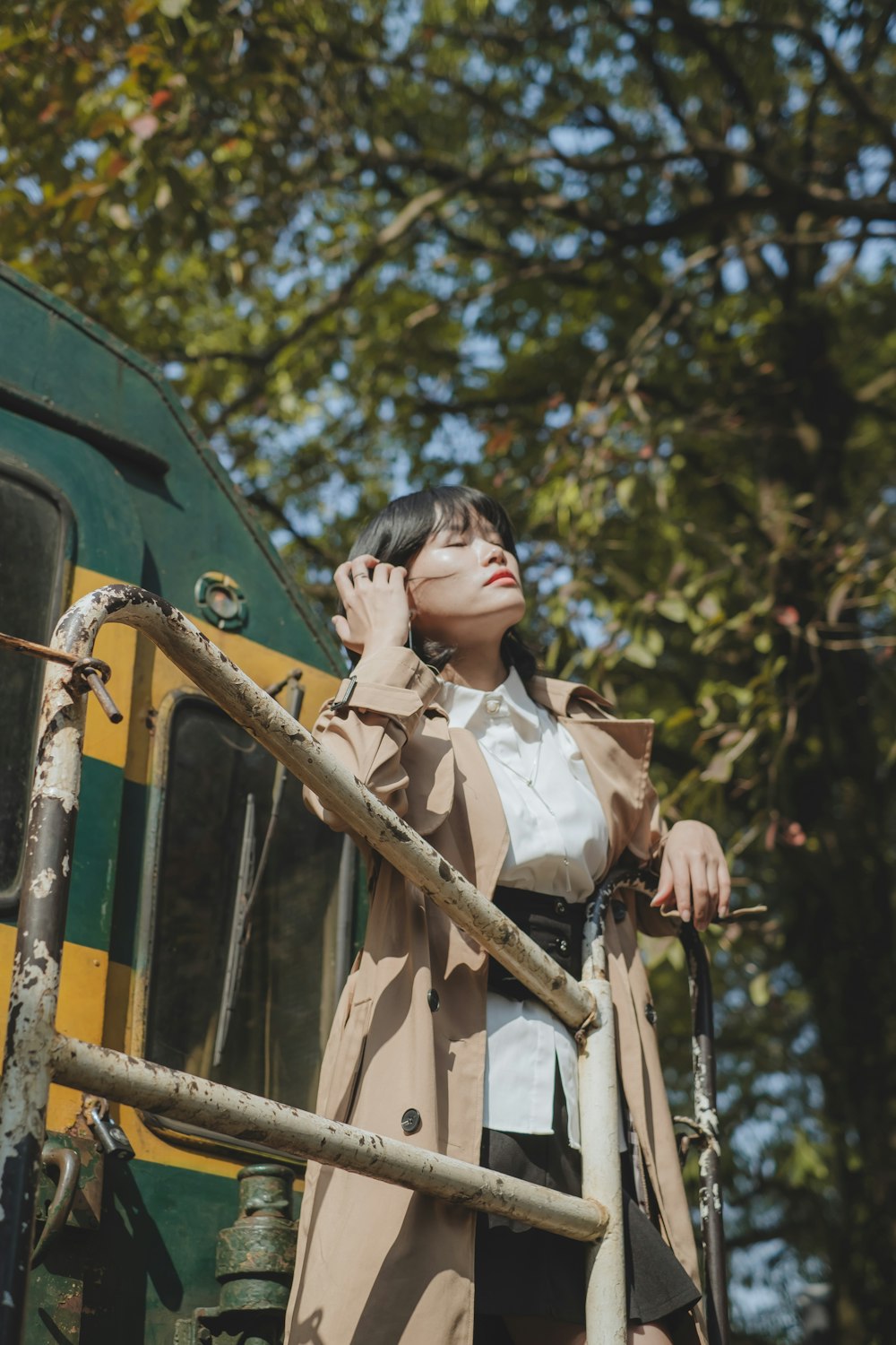 a woman in a trench coat leaning on a rail