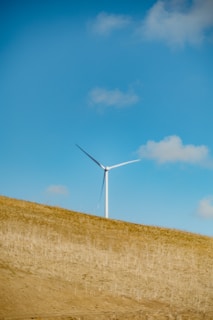 a wind turbine on a hill under a blue sky