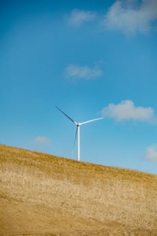a wind turbine on a hill under a blue sky