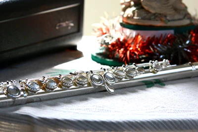 A shiny silver flute catching the light on a dark wooden table.